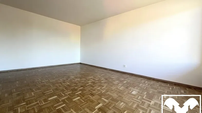 Heller, leerer Raum mit Fischgrätparkettboden und weißen Wänden, bereit zur individuellen Gestaltung.