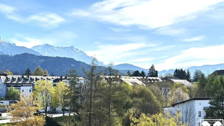 Panoramablick auf die umliegende Berglandschaft und die Dächer der Häuser in der Ferne.