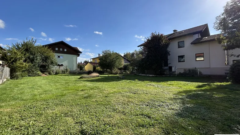 Großer Rasenbereich mit umliegenden Häusern unter blauem Himmel an einem sonnigen Tag.