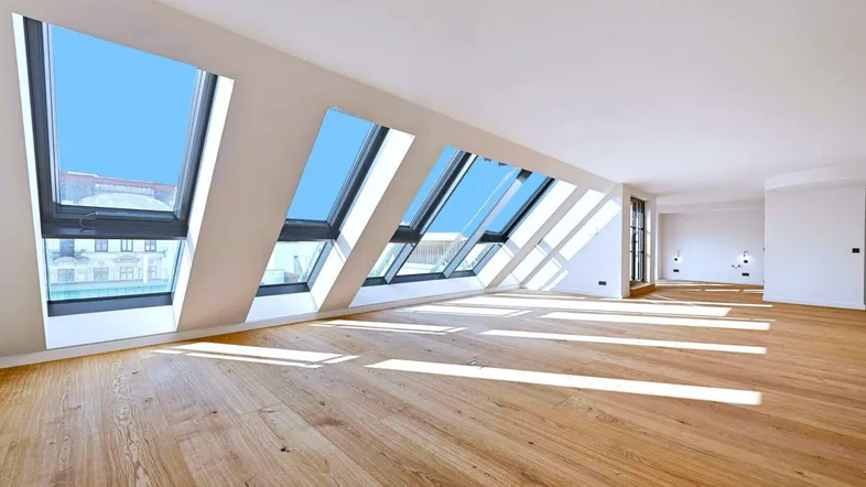 Heller, offener Raum mit Holzboden und zahlreichen Dachfenstern, die viel Tageslicht hereinlassen.