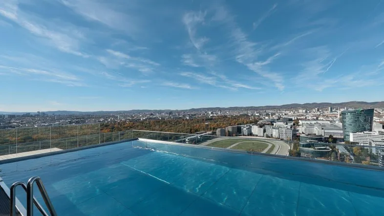 Infinity-Pool auf dem Dach mit atemberaubendem Blick über die Stadt und die umliegende Landschaft.