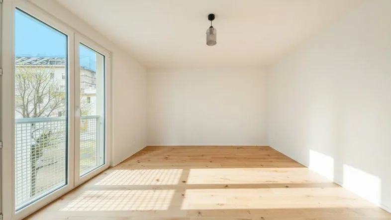 Helles Zimmer mit Holzboden und großen Fenstern, die viel Tageslicht hereinlassen und einen französischen Balkon bieten.