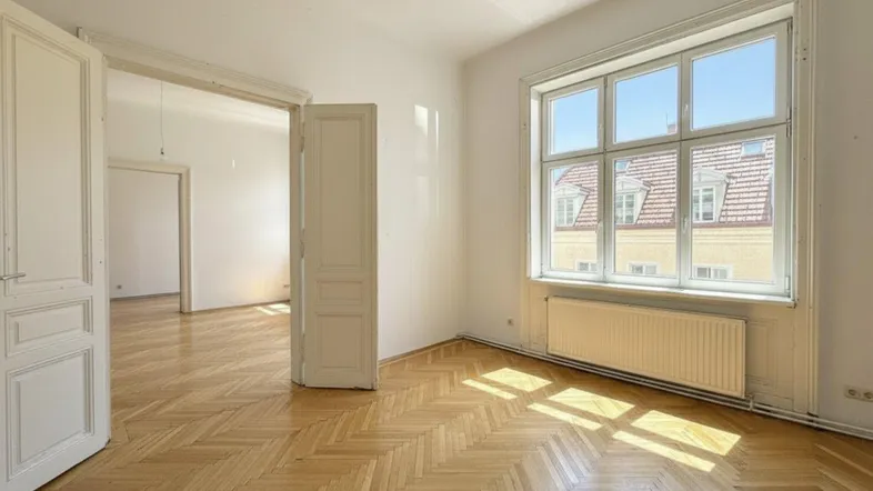 Helles Wohnzimmer mit Fischgrätparkett, großen Fenstern und Blick auf die umliegenden Gebäude.