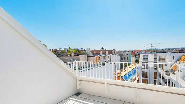 Sonnige Dachterrasse mit weißem Geländer und weitem Blick über die Stadt.