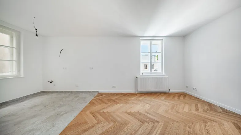 Helles Zimmer mit Fischgrätparkett und einem Bereich, der auf die Fertigstellung wartet.