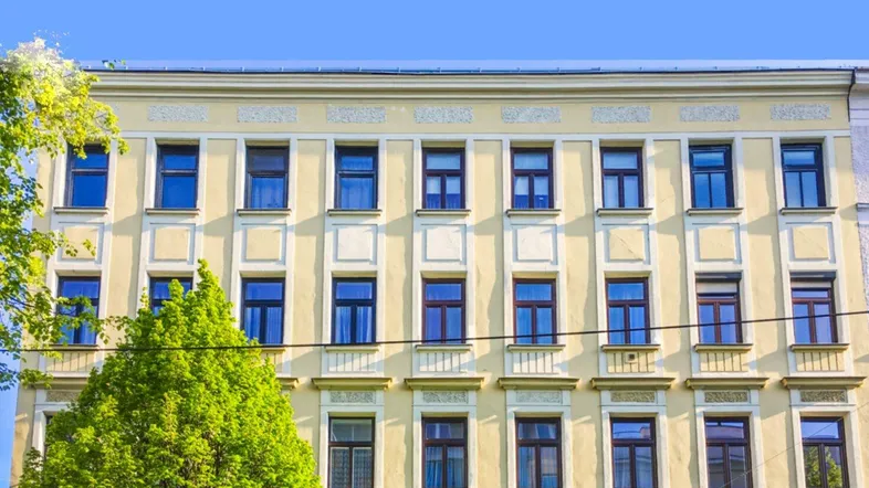 Historische Fassade eines Mehrfamilienhauses mit vielen Fenstern und klassischer Architektur.