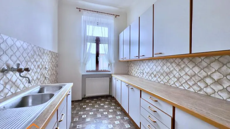 Helle Küche mit weißen Schränken, Holzoptik-Arbeitsplatten und gemusterten Fliesen.