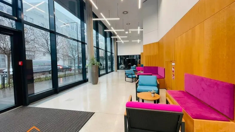 Moderner Empfangsbereich mit großen Glasfassaden, bequemen Sitzgelegenheiten und stilvoller Beleuchtung.