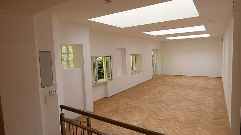 Geräumiger, heller Wohnbereich mit Fischgrätparkett und großen Dachfenstern, die viel Tageslicht hereinlassen.