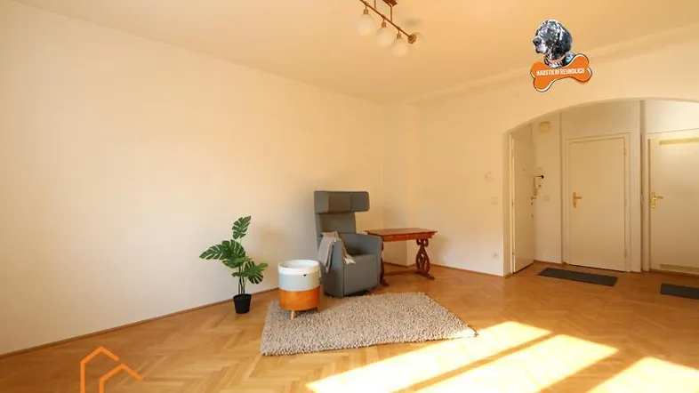Helles Wohnzimmer mit Parkettboden, einem Sessel und viel natürlichem Licht durch das Fenster.