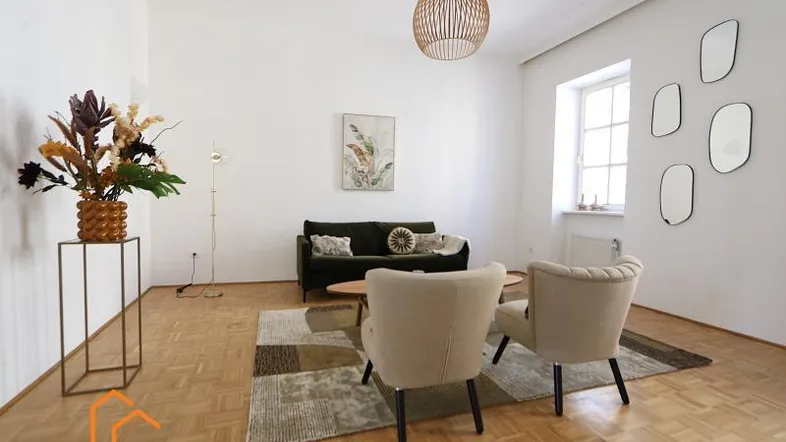 Helles Wohnzimmer mit Parkettboden, modernen Möbeln und dekorativen Spiegeln an der Wand.