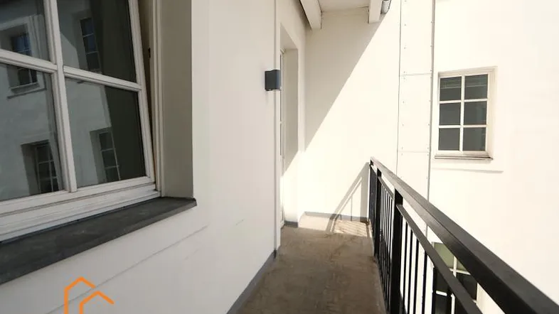 Schmaler, überdachter Außenbereich mit Geländer und Blick auf den Innenhof.