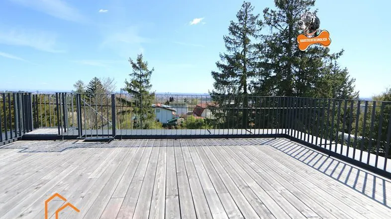 Große Dachterrasse mit Holzboden und weitem Blick über die Landschaft unter blauem Himmel.
