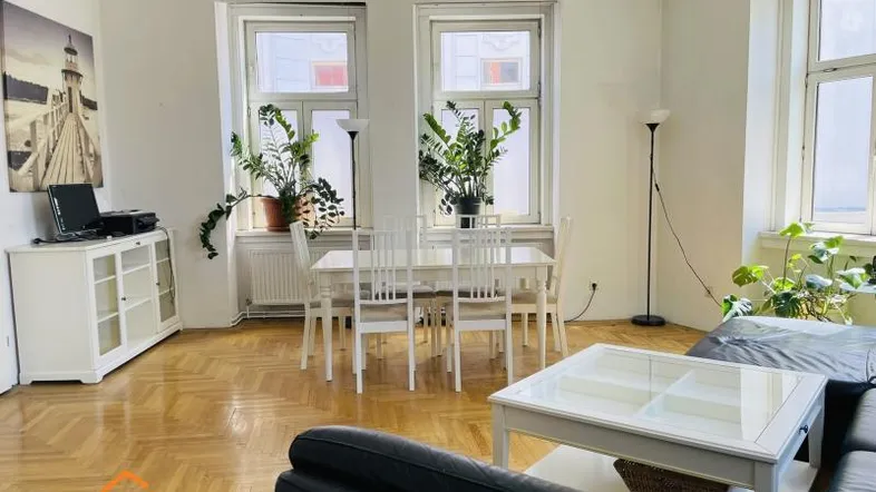 Helles Wohn- und Esszimmer mit Fischgrätparkett, weißem Mobiliar und großen Fenstern.