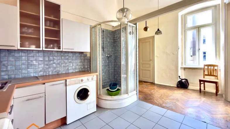 Küche in einem Altbau mit Fliesenboden, Einbauschränken und einer integrierten Duschkabine.