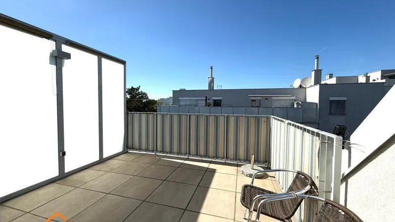 Geräumige Dachterrasse mit Fliesenboden und Sitzgelegenheiten unter blauem Himmel.