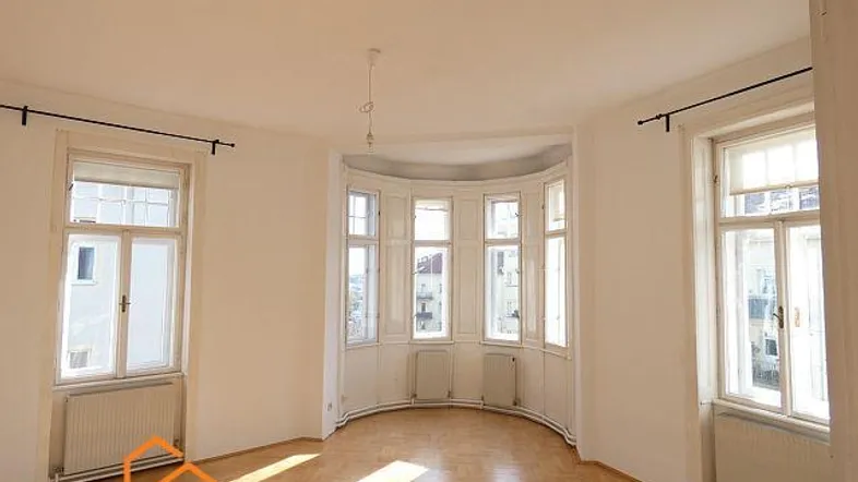 Helles Wohnzimmer mit Fischgrätparkett, großen Bogenfenstern und viel Tageslicht.