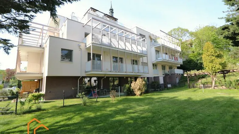 Modernes Mehrfamilienhaus mit mehreren Balkonen und einer weitläufigen Rasenfläche im Vordergrund.
