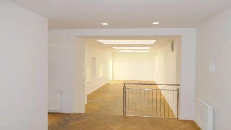 Heller, offener Raum mit Fischgrätparkettboden und moderner Galeriebrüstung, ideal für vielseitige Nutzung.