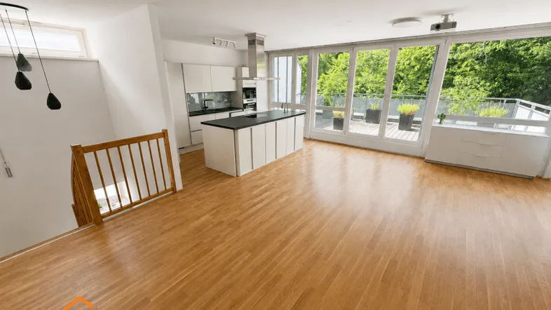 Heller offener Wohnbereich mit moderner Küche, Holzboden und Zugang zu einer großen Terrasse.