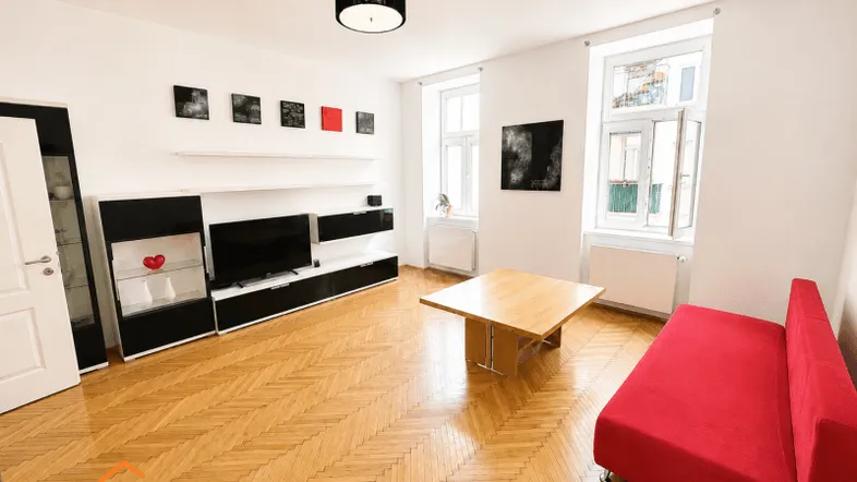 Helles Wohnzimmer mit Fischgrätparkett, rotem Sofa und moderner Medieneinheit.