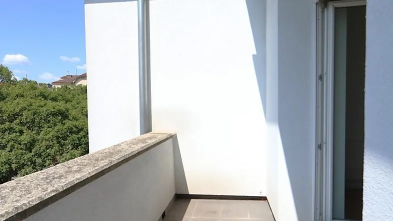 Heller Balkon mit Fliesenboden und Blick ins Grüne, ideal für entspannte Stunden im Freien.
