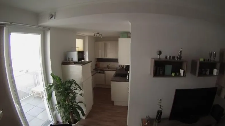 Heller Wohn- und Essbereich mit Zugang zum Balkon und offener Küche.