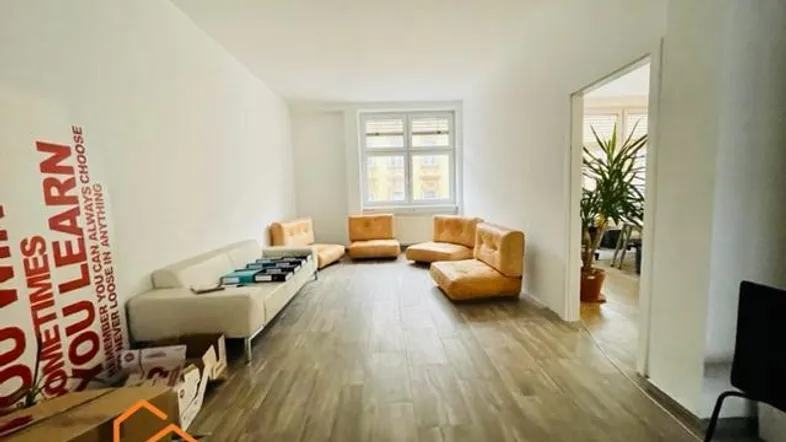 Geräumiger Lounge-Bereich mit bequemen Sofas und Sesseln, hellen Wänden und Laminatboden.