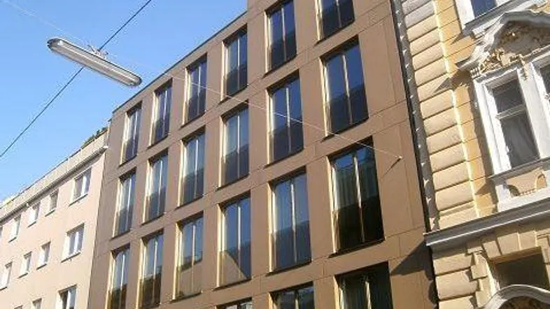 Moderne Fassade eines Neubaus mit vielen großen Fenstern und klaren Linien.