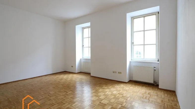 Helles Zimmer mit Fischgrätparkettboden und zwei Fenstern, ideal als Wohn- oder Schlafzimmer.