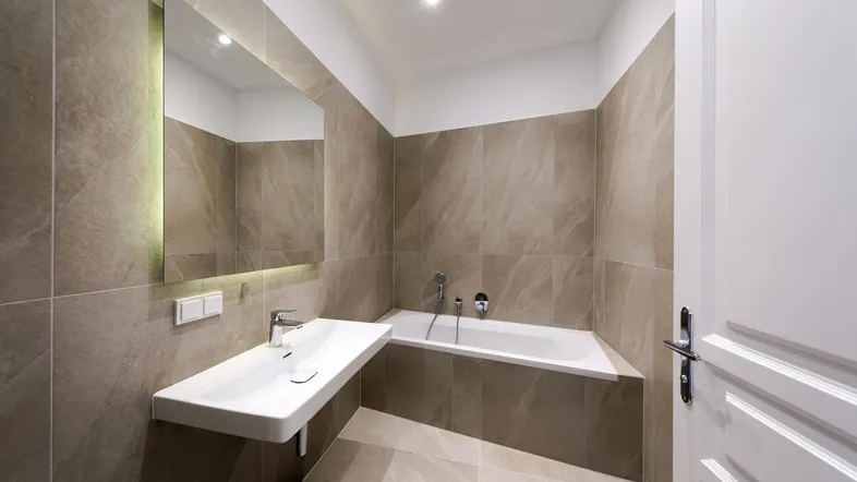 Modernes Badezimmer mit Badewanne, schwebendem Waschbecken und großformatigen Fliesen.