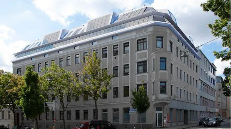 Gebäudeansicht von der Straße mit moderner Dachkonstruktion und klassischer Fassade.