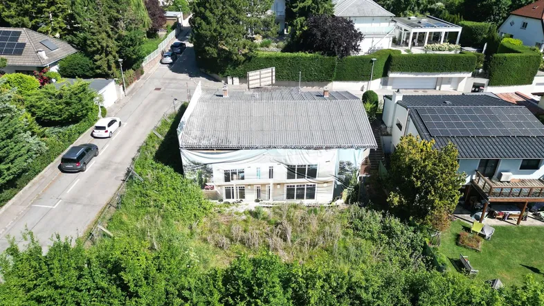 Luftaufnahme eines Hauses im Bau mit umliegender Wohnbebauung und viel Grün.
