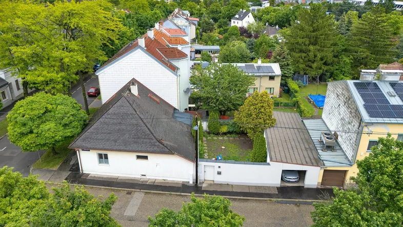 Luftaufnahme eines Wohnhauses mit Garten und Garage in einer grünen Wohngegend.
