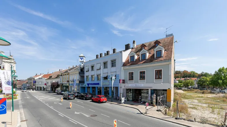 Blick auf eine belebte Straße mit verschiedenen Gebäuden und Geschäften unter blauem Himmel.