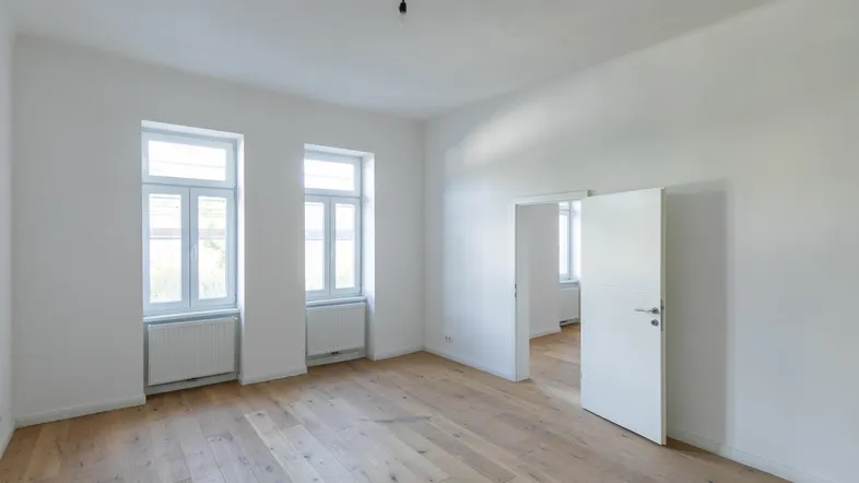 Helles Zimmer mit Holzboden und weißen Wänden, bereit für die individuelle Gestaltung und Nutzung.