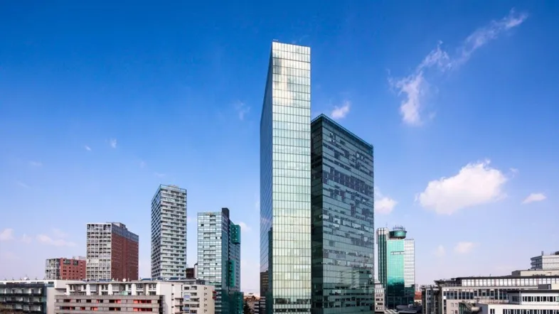 Panoramablick auf eine moderne Skyline mit hohen Glasgebäuden unter blauem Himmel und wenigen Wolken.