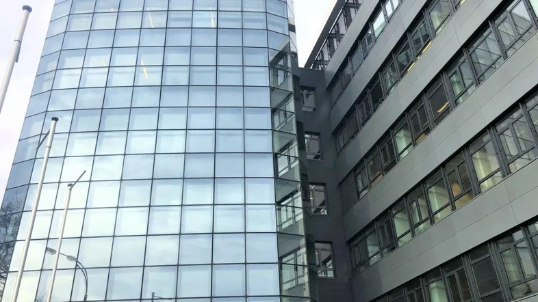 Modernes Bürogebäude mit beeindruckender Glasfassade und vielen Fenstern, das eine zeitgenössische Architektur zeigt.