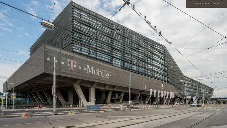 Großes, modernes Geschäftsgebäude mit Glasfassade und T-Mobile-Branding an einer belebten Straße.