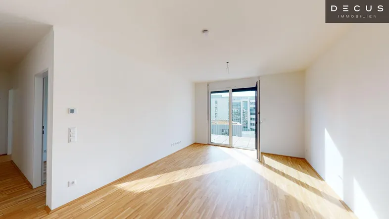 Helles Zimmer mit Parkettboden und Zugang zu einem Balkon, ideal als Wohnbereich nutzbar.
