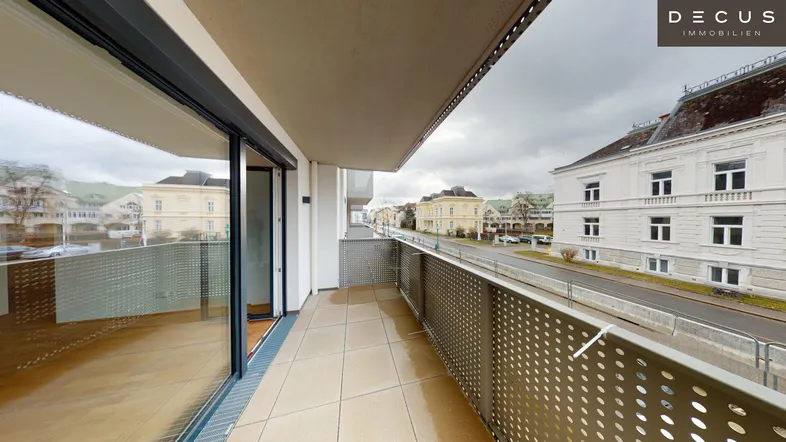 Geräumiger Balkon mit Fliesenboden und Blick auf die umliegende Stadtstraße und Gebäude.