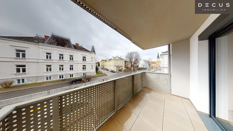 Geräumiger Balkon mit Fliesenboden und Blick auf die Stadt und umliegende Gebäude.