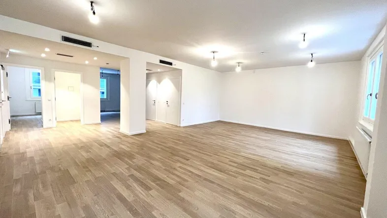 Großer, heller Raum mit Holzboden und weißen Wänden, bereit für individuelle Gestaltung und Nutzung.