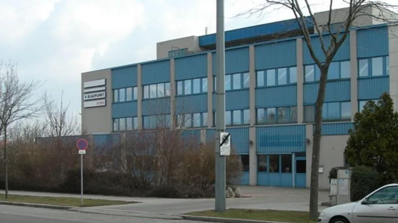 Gebäudeansicht eines Gewerbeobjekts mit blauer Fassade und großen Fenstern an einer Straße.