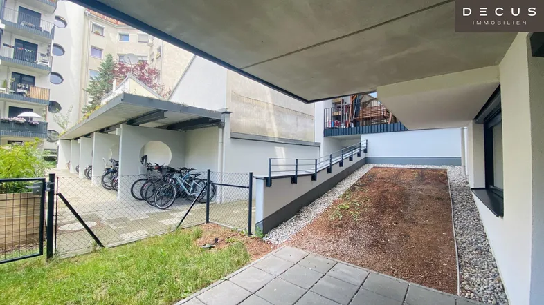 Fahrradabstellplätze unter einem Unterstand und ein kleiner Gartenbereich im Außenbereich der Wohnanlage.