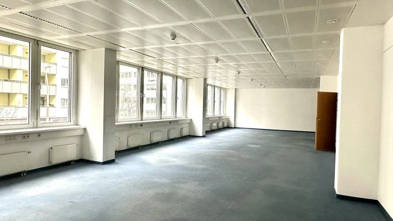 Geräumiges Büro mit Teppichboden und vielen Fenstern, die viel Tageslicht hereinlassen.