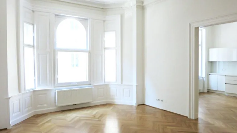 Helles Wohnzimmer mit Fischgrätparkett, Stuckdecken und einem schönen Erkerfenster.