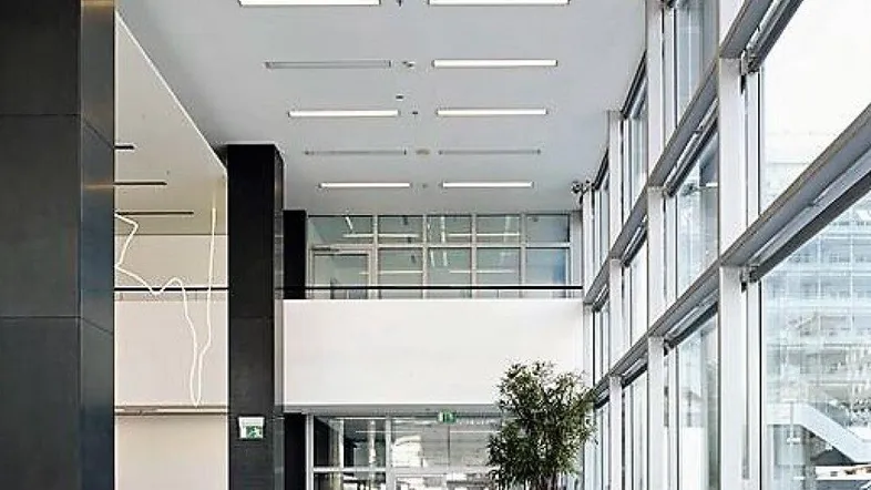 Geräumige, moderne Lobby mit hohen Decken, großen Fenstern und stilvollen weißen Sitzgelegenheiten.
