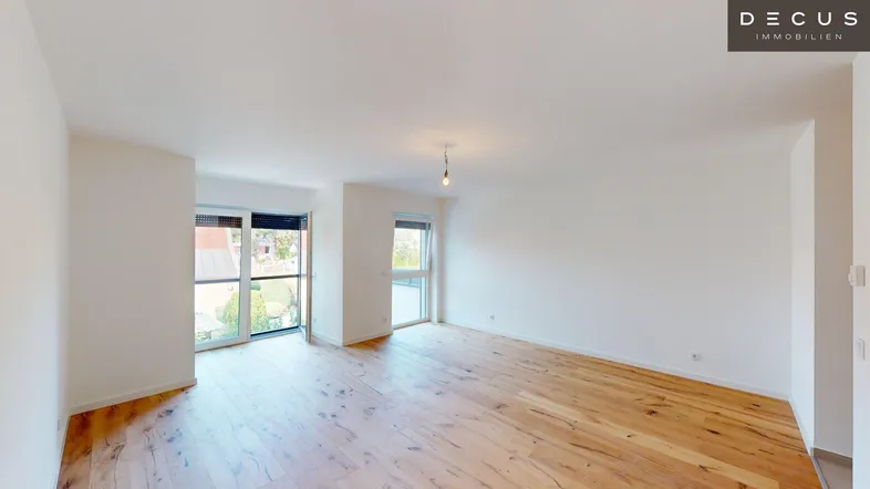 Heller, leerer Wohnbereich mit Holzboden und Zugang zu einem Balkon, der viel Tageslicht bietet.