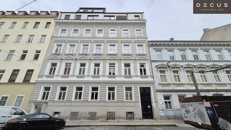 Ansicht der historischen Fassade eines Mehrfamilienhauses mit klassischer Architektur und modernen Dachaufbauten.